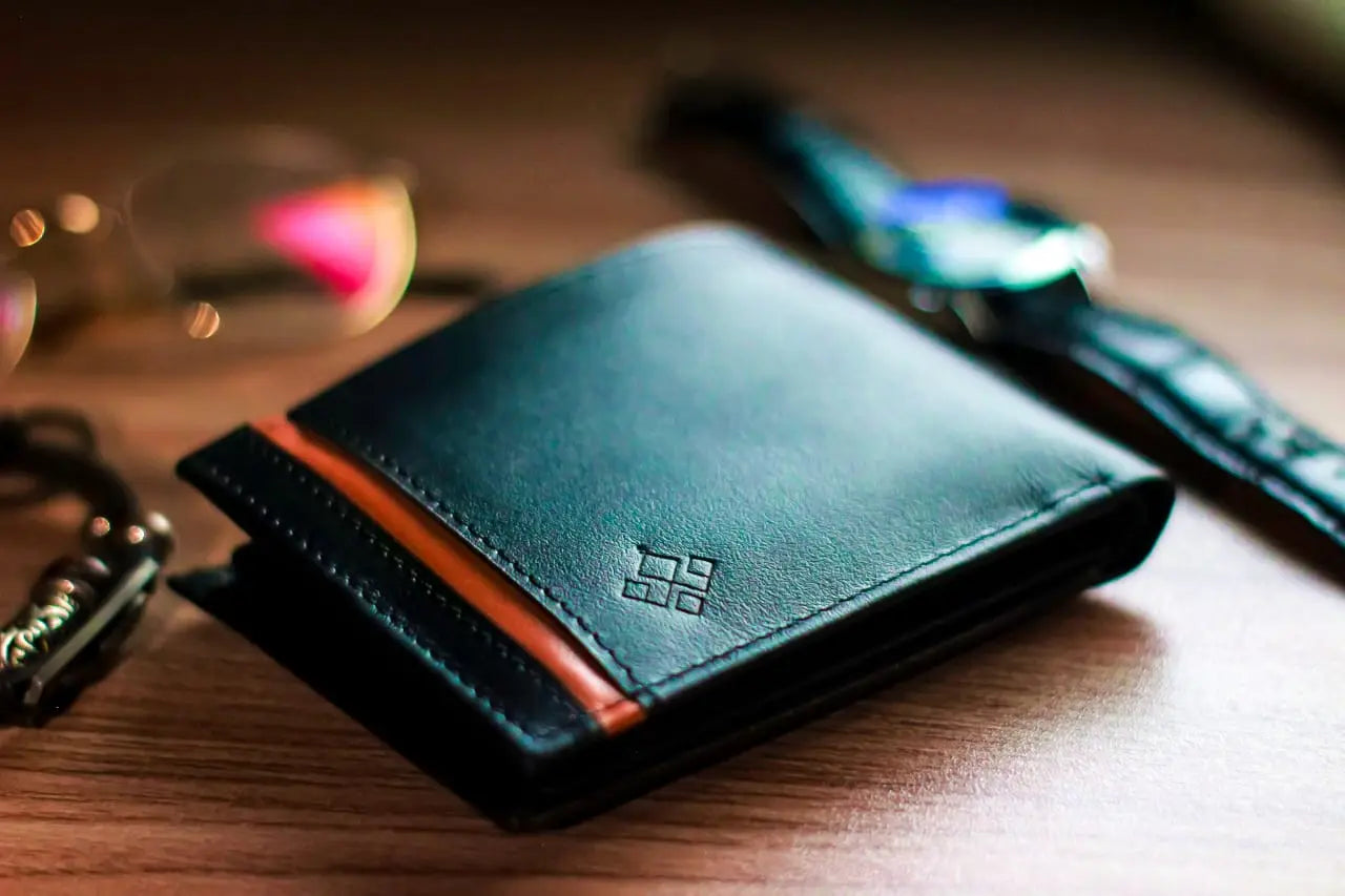 Green leather wallet with an orange stripe on a wooden surface