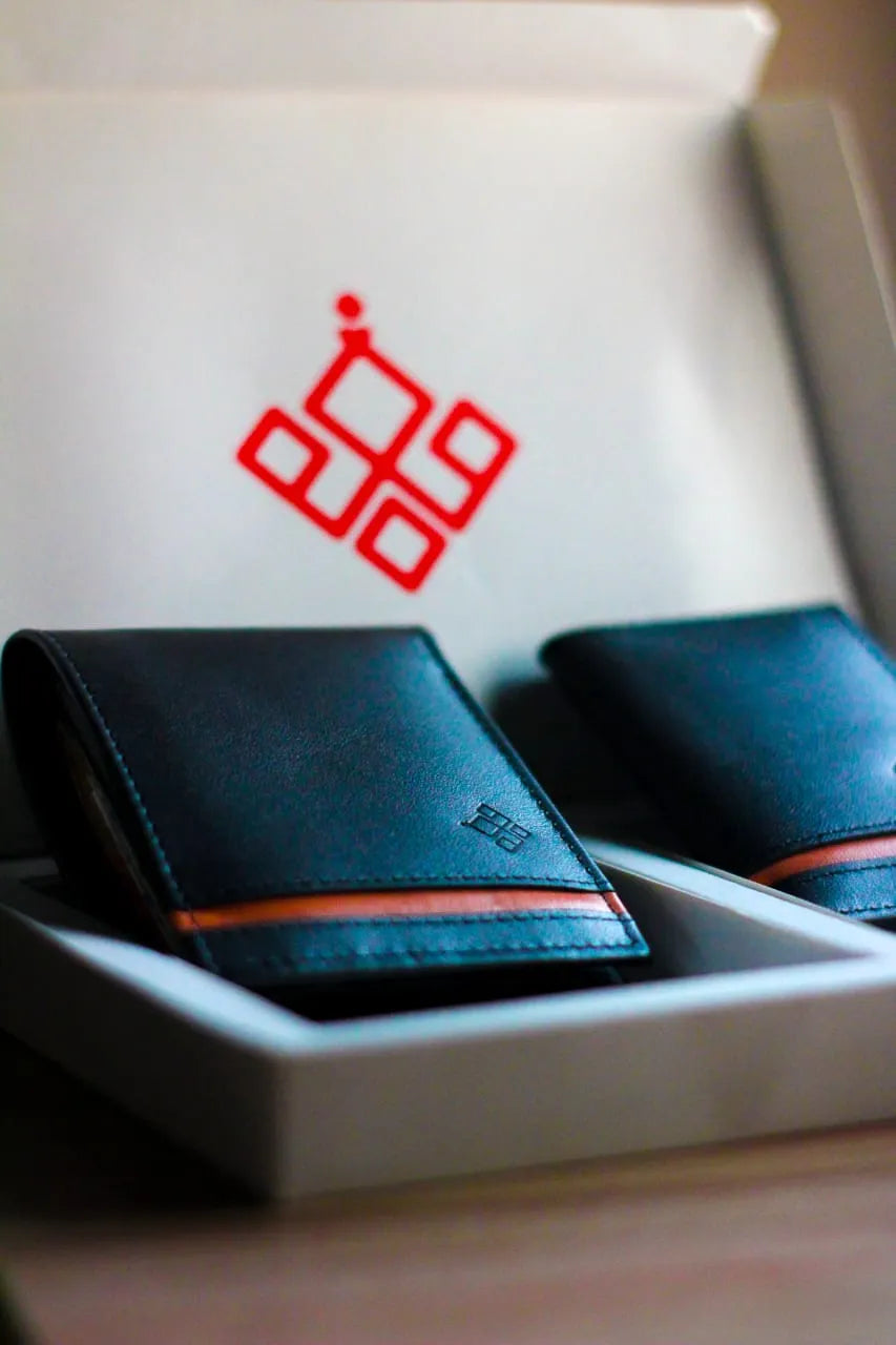 Two black leather wallets with red accents in a box featuring a red logo.